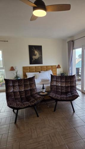 a bedroom with two chairs and a bed with a ceiling fan at פסטרנק אירוח יער אודם in Odem