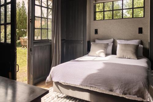 a bedroom with a bed with white sheets and windows at Neska Lodge in Saint-Rémy-lʼHonoré