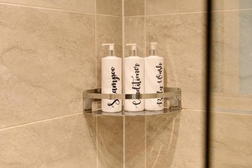 a group of four white bottles on a shelf in a bathroom at Coast Beachfront GF 6 guests dog friendly apartment in Southbourne