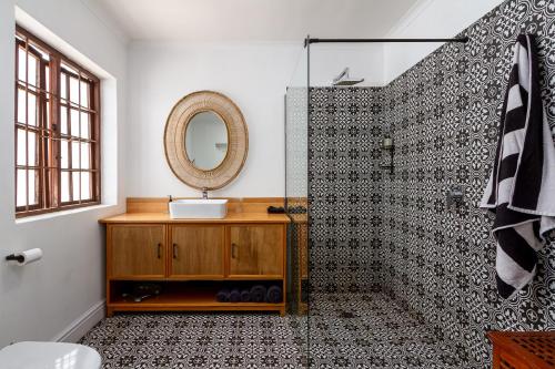 a bathroom with a shower with a sink and a mirror at Noordhoek Village Hotel in Noordhoek