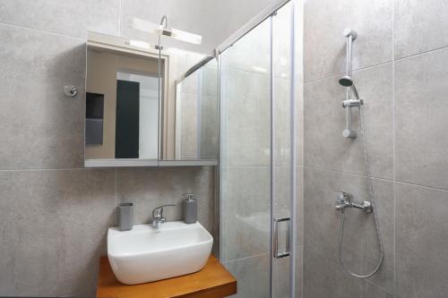 a bathroom with a sink and a shower with a mirror at Samà Housing in Larisa