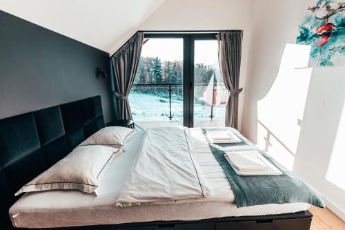 a bedroom with a bed with a large window at Wood Lake Rożnów in Rożnów