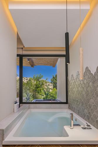a bathroom with a large tub with a large window at Avaton Boutique Suites in Vrachonisída touArchangélou