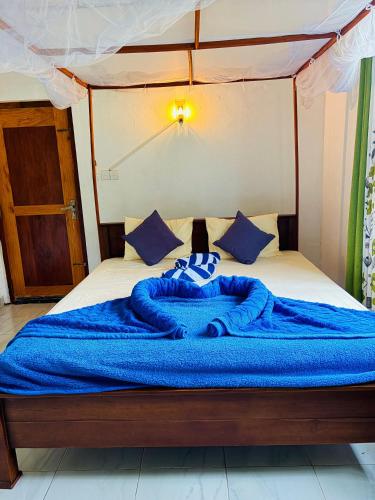 a bed with a blue blanket on top of it at Hiriketiya Lima Homestay in Dickwella