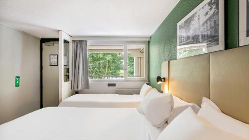 a hotel room with two beds and a window at Campanile Brive-La-Gaillarde Ouest in Brive-la-Gaillarde