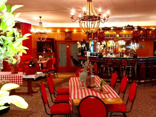 een restaurant met een bar met rode stoelen en tafels bij Hotel Georgenhöhe Wildemann in Wildemann