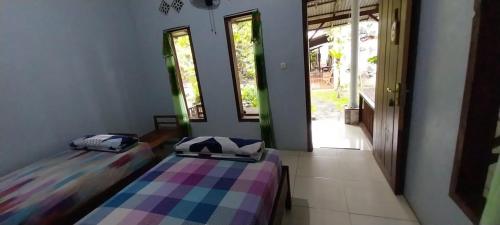 two beds sitting in a room with a window at Hadi Homestay Garden View in Jambu
