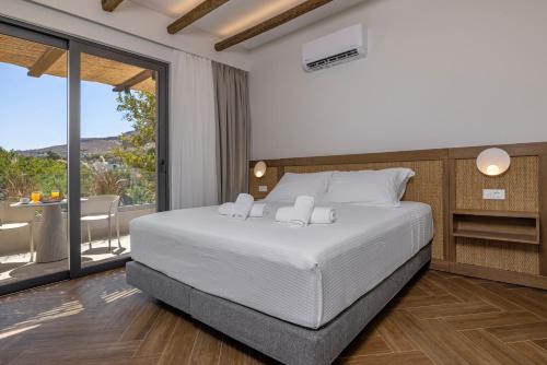 a bedroom with a white bed and a balcony at Avaton Boutique Suites in Vrachonisída touArchangélou