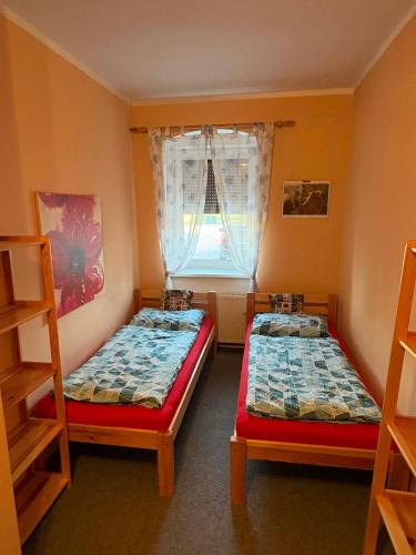 two beds in a room with a window at Apartmány Somora in Doksy