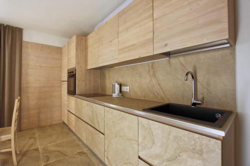 una cucina con mobili in legno e un lavello di Appartamento Alpen Molveno a Molveno