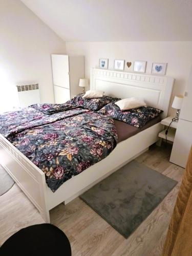 a bedroom with a large white bed with floral sheets at Apartmán Romanna in Terchová