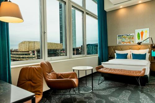 een hotelkamer met een bed, een stoel en ramen bij Motel One Leipzig-Post in Leipzig