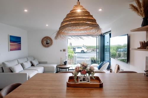 a living room with a large wooden table with flowers on it at Coast Beachfront GF 6 guests dog friendly apartment in Southbourne