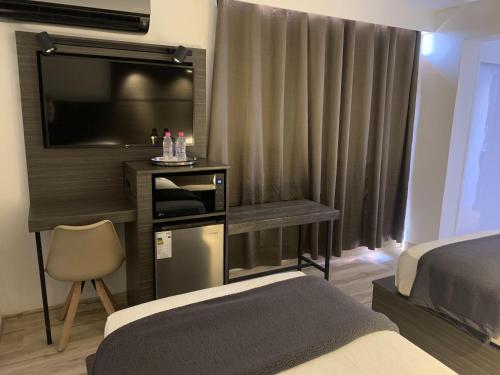 een slaapkamer met een bed en een flatscreen-tv bij Hotel Princesa Plaza in Maracay