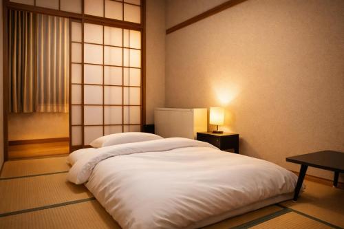 a large white bed in a room with a window at Resort Project Myoko Kogen Hot Spring in Myoko