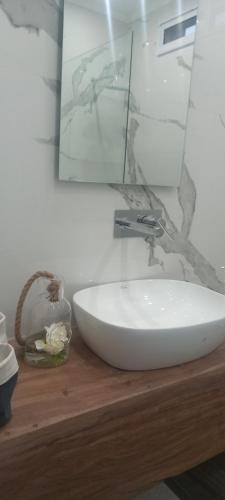 a white sink on a wooden counter with a mirror at Entre Jazmines & Glicinas in Lobos