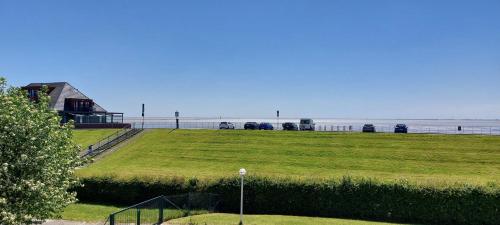a field of grass with the ocean in the background at Exklusive Ferienwohnung am Südstrand mit Wintergarten & Hafenblick Wohnung 113 in Wilhelmshaven