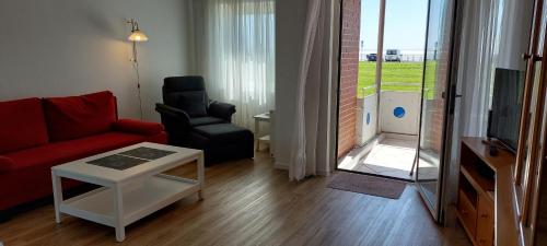 a living room with a red couch and a chair at Exklusive Ferienwohnung am Südstrand mit Wintergarten & Hafenblick Wohnung 113 in Wilhelmshaven
