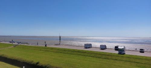 a beach with a row of trash cans next to the water at Exklusive Ferienwohnung am Südstrand mit Wintergarten, Balkon & Meerblick Wohnung 22 in Wilhelmshaven