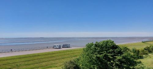 two trucks driving down a road next to the beach at Exklusive Ferienwohnung am Südstrand mit Wintergarten, Balkon & Meerblick Wohnung 22 in Wilhelmshaven