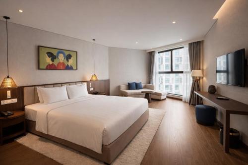 a bedroom with a bed and a desk and a television at Mandala Mui Ne - Beach & Pool Suites in Mui Ne