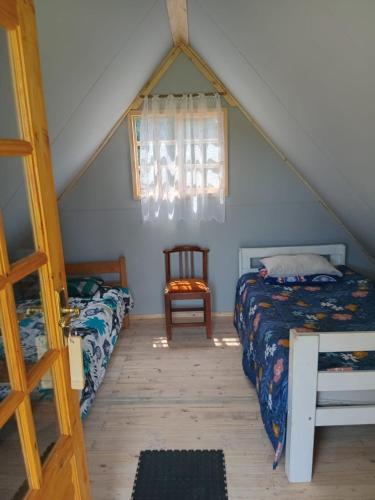 a attic bedroom with two beds and a window at Dam Jam Cabanas in Oranjeville