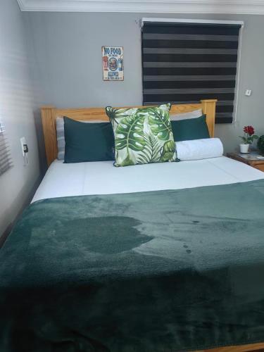 a bedroom with a large bed with green sheets and pillows at The Hideaway Cabin in Pretoria