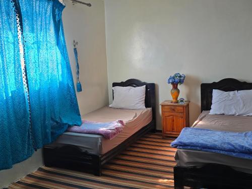 a room with two beds and a vase of flowers at tigmi oufla in Taghazout