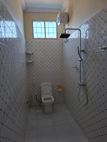 a bathroom with a toilet and a shower and a window at Karibu House Bwejuu in Bwejuu