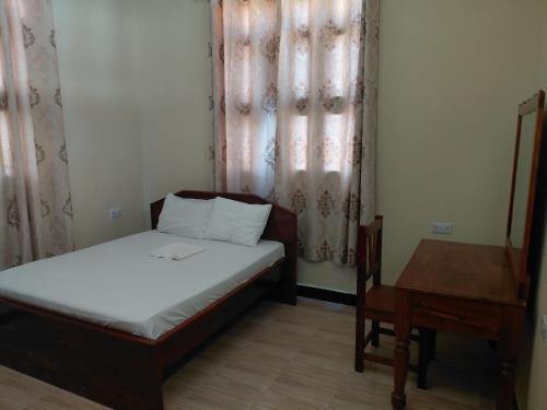 a small bedroom with a bed and a table at Karibu House Bwejuu in Bwejuu