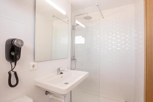 ein weißes Badezimmer mit Waschbecken und Dusche in der Unterkunft Hotel Sultán in Can Picafort