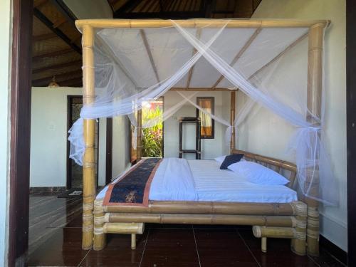 a bed with a canopy in a room at Tutwin Guesthouse in Krambitan