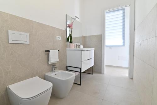 a white bathroom with a toilet and a sink at Congiu's Apartments in Pula
