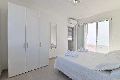a white bedroom with a large bed and a window at Congiu's Apartments in Pula