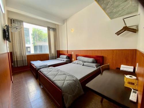a bedroom with two beds and a table and a window at Văn An Hotel in Ho Chi Minh City