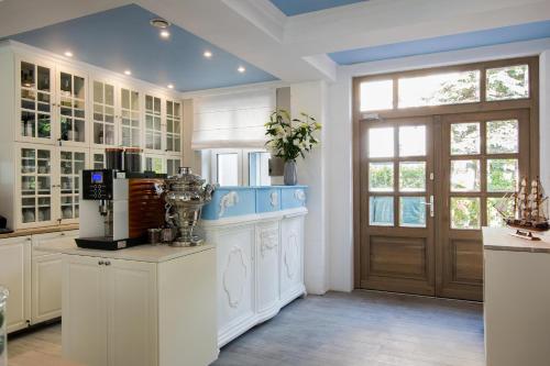 a large kitchen with white cabinets and a door at Willa Błękit Hotel by Dorota Szelągowska in Mielno