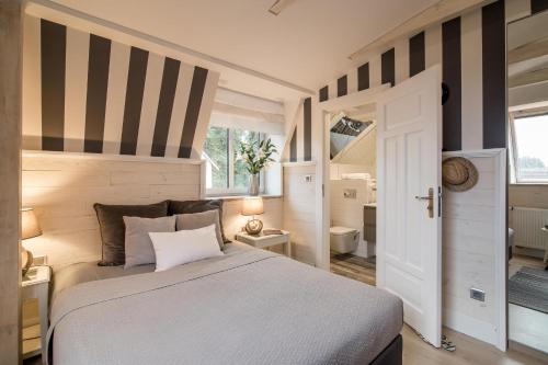 a bedroom with a bed with a striped wall at Willa Błękit Hotel by Dorota Szelągowska in Mielno