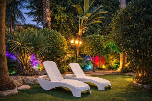 Twee witte stoelen staan 's nachts in een tuin. bij Private Villa with Heated Pool and Jacuzzi in Rishon LeẔiyyon