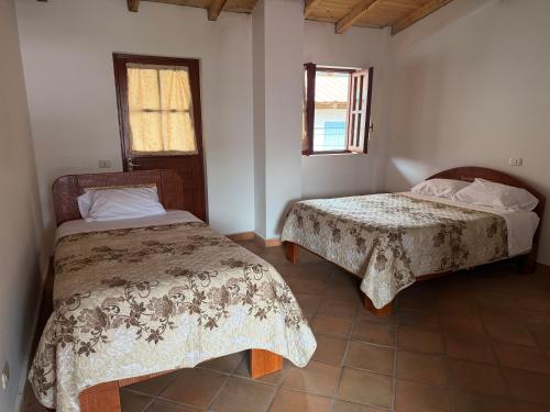 a bedroom with two beds and a window at Alonso, Fogón & Posada in Chacas