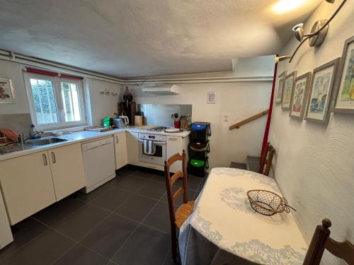 una cucina con mobili bianchi e un tavolo e un tavolo e un tavolo di Chez Zabou a Carpentras