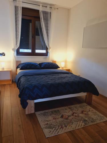 a bedroom with a bed with blue sheets and a window at OLD TOWN ROAD in Karlovac