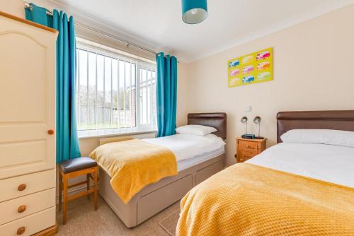 zwei Betten in einem Schlafzimmer mit blauen Vorhängen in der Unterkunft 2 Bed in Reydon oc-lowrd in Reydon