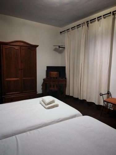 a bedroom with a bed with white sheets and a wooden cabinet at Hostal Casa Inés La Valerosa in Las Navas de la Concepción