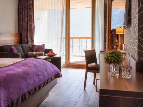 een slaapkamer met een paars bed en een bank bij Das Kronthaler - Adults only in Achenkirch