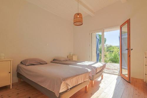 a bedroom with two beds and a large window at Villa des Amandes in Bédarieux