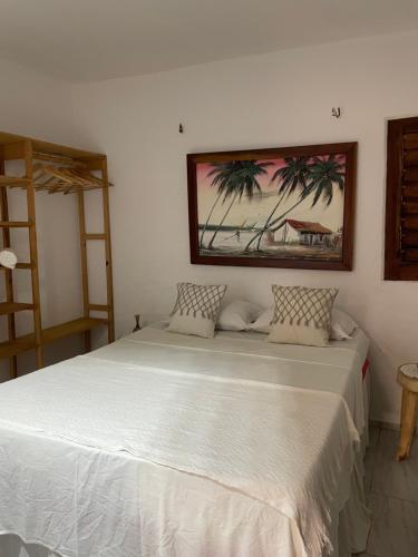 a bedroom with a white bed with a painting on the wall at Casa De Vó in Amontada
