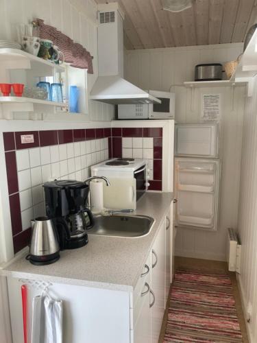 een kleine keuken met een spoelbak en een fornuis bij Lugnt och centralt in Strömstad