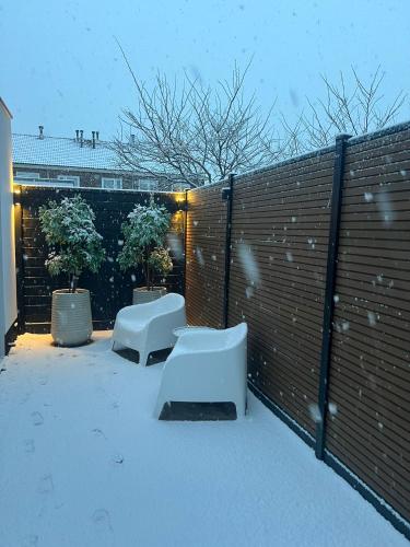 a snowy yard with two benches and a fence at Vakantie in Noordwijk in Noordwijk