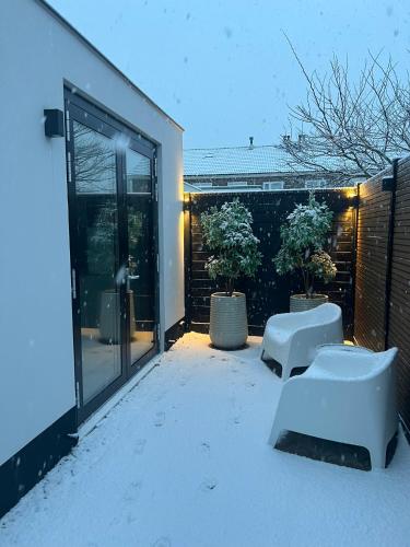 a patio with snow covered furniture and a building at Vakantie in Noordwijk in Noordwijk