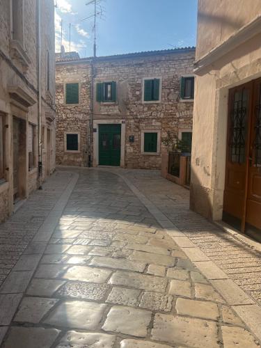 an alley in an old stone building with a green door at Nesa Beach Front Apartment in Poreč